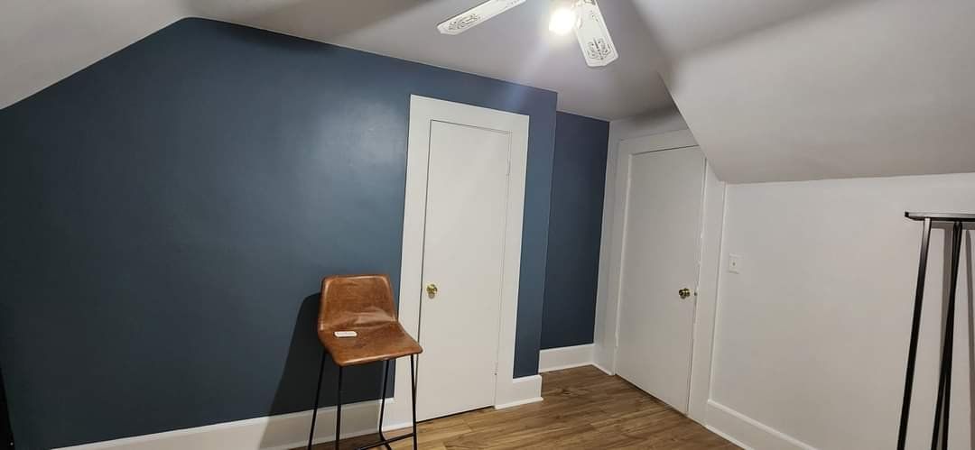 Bedroom with a deep navy accent wall, white doors and a sloped white ceiling