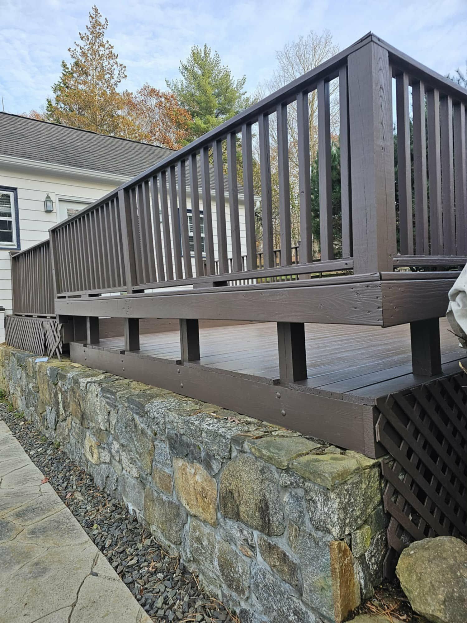 Stained deck railing above a fieldstone retaining wall