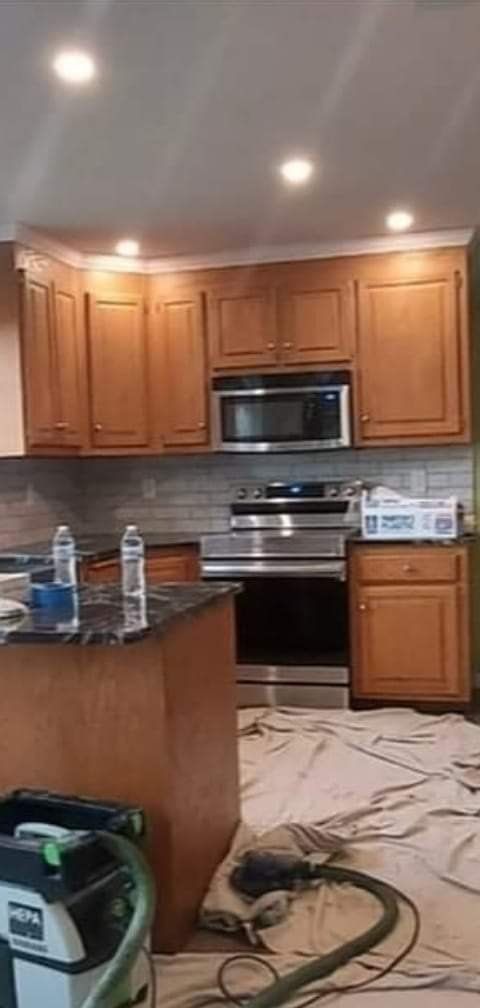 The same kitchen before, with honey oak cabinets and drop cloths on the floor
